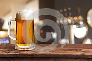 Cold beer glass on wood table and blur pub background