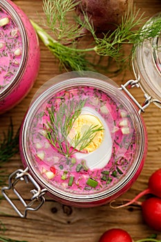 Cold beetroot soup, cold served with the addition of cucumbers, radishes, boiled eggs and fresh herbs, dill, green onions in glass