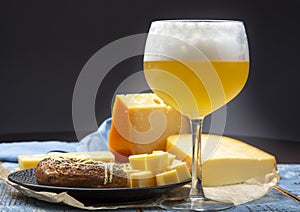 Cold belgian beer in glass served in cafe with variety of hard cheeses, tasty european food