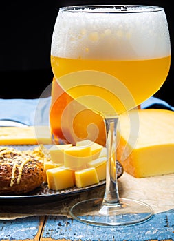 Cold belgian beer in glass served in cafe with variety of hard cheeses, tasty european food