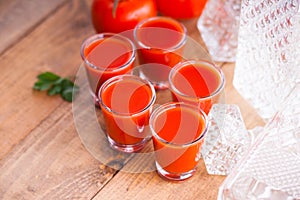Cold Bloody Mary cocktail shot in glasses and tomatoes
