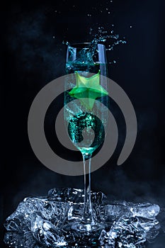 Blue cocktail with a star fruit garish on black background