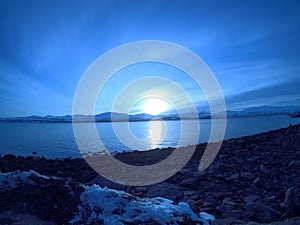 Cold blue fjord and snowy mountain landscape with sunset