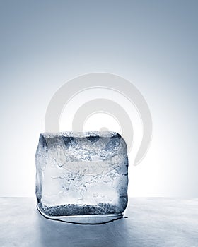 Cold blue ice block melting into water on metal surface