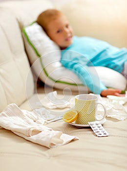 Cold boy lying on the bed, in front of him as lemon, tea,