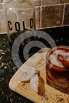 Cold brew coffee in a glass with ice, with a cold brew jar, ice