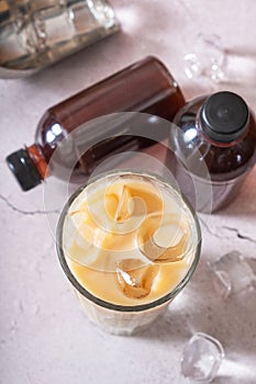 Cold brew coffee with milk and cold brew coffee in bottles with ice cubes top view