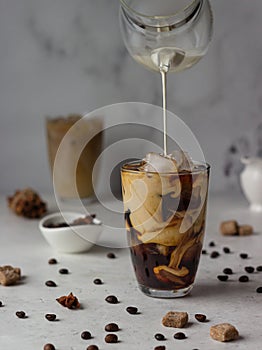 Cold brew coffee with spices and milk on light grey background.