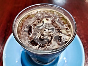 Cold brew iced fresh Americano coffee served in a glass on wooden table