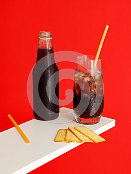 Cold carbonated drink with ice and soft drink bottle and Cracker Biscuit isolated on red background