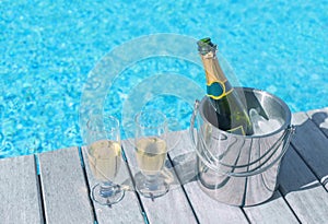 Cold champagne bottle in ice bucket and two glasses of champagne on the deck by the bottle in bucket and two glasses of champagne