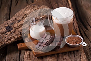 Cold Chocolate Milk drink and chocolate bar on wooden background
