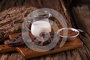 Cold Chocolate Milk drink and chocolate bar on wooden background