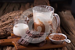 Cold Chocolate Milk drink and chocolate bar on wooden background