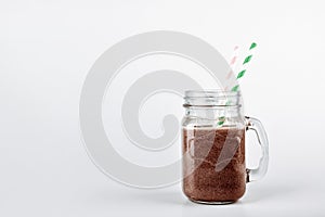 Cold chocolate milkshake in a glass jar with a straw