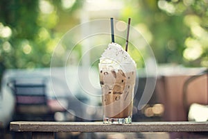 Cold chocolate with whipped cream topping in glass on summer nat