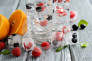 Cold cocktail with forest berries, frozen in ice cubes