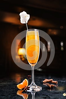 Cold cocktail with tangerines, gold, cotton candy and champagne in tall glass on backdrop of the restaurant atmosphere