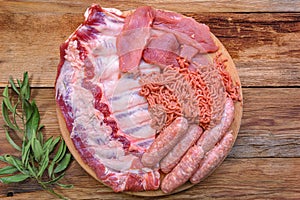 Cold cuts. raw pork ribs, minced meat, sausages, and carbonate on a round cutting board. Condiments for cooking meat dishes close-