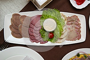 Cold cuts on a rectangular white plate.