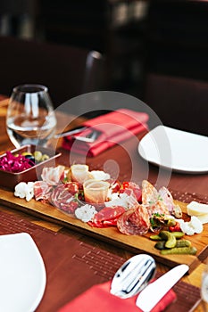 Cold cuts on wooden board with prosciutto, bacon, salami and sausages. Meat platter appetizers served with pickle and olives.