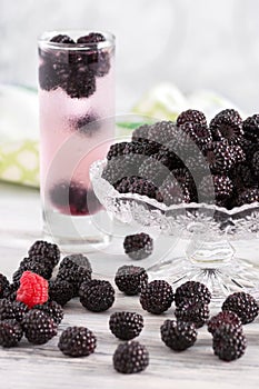 A cold drink with black raspberries . Vase with raspberries . Raspberry on a wooden table.