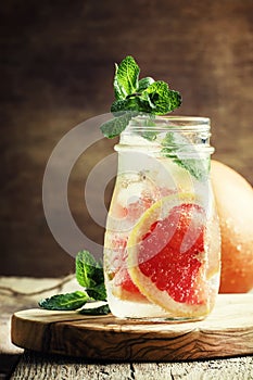 Cold drink with grapefruit and soda, mint and ice in a glass bot
