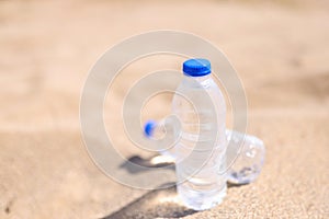 Cold drinking water in transparent bottles on sandy beach sea