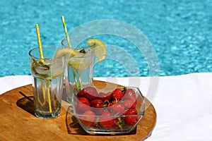 Cold drinks with lemons and bowl of strawberries