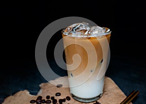 Cold espresso coffee on iced with milk. Iced coffee in tall glass on dark background ideal for cafe beverage menu.m Black backgrou