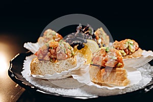 Cold fish appetizer on a black plate on a black background