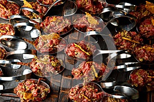 Cold fish appetizers on a metal spoon, on a wooden black board