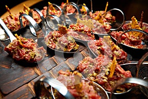 Cold fish appetizers on a spoon, on a wooden black board