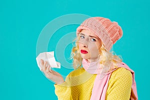 Cold and flu season- portrait of a woman in hat and scarf holding tissue