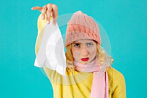 Cold and flu season- portrait of a woman in hat and scarf holding tissue