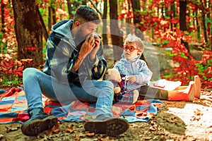Cold flu season, runny nose. Cute boy with Father on Fall Nature Background. Childhood concept. Father with handkerchief