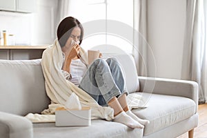 Cold And Flu. Sick young woman blowing her nose and drinking tea