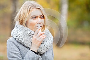 Cold and flu. Young sick woman uses a nose spray at street outside