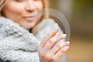 Cold and flu. Young sick woman uses a nose spray at street outside