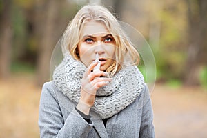 Cold and flu. Young sick woman uses a nose spray at street outside