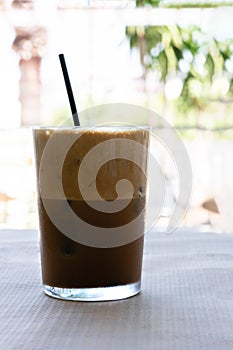 Cold frappe coffee with ice cubes on glass with black straw served on the table in caffeteri