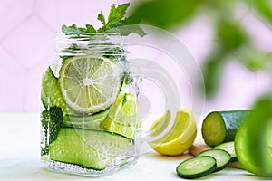 Cold fresh summer drink in glass. Tasty lemonade with lemon, lime, cucumber, mint and ice. Close up. Selective focus. Blurred