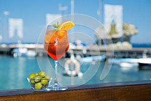Cold glass of aperol spritz near the sea and boats