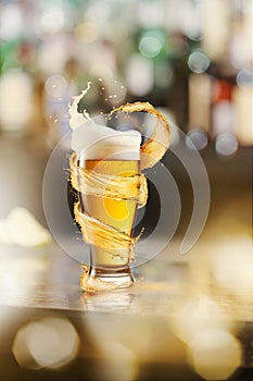 A cold glass of beer and a splash around on a blurred bar counter background