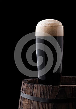 Cold glass of dark stout beer on wooden barrel