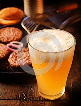 Cold glass of frothy beer with burger patties photo