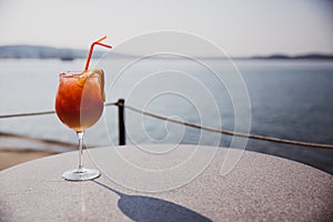 Cold glass of Rum swizzle stand on table near the sea