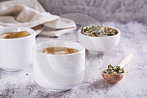 Cold green Japanese hojicha tea with ice in cups and dry tea in a bowl on the table