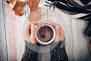 Cold hands catching cup of hot chocolate in autumn top