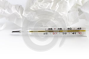 Cold, high temperature concept. Glass mercury thermometer with celsius degree and napkins. Thermometer close-up on white